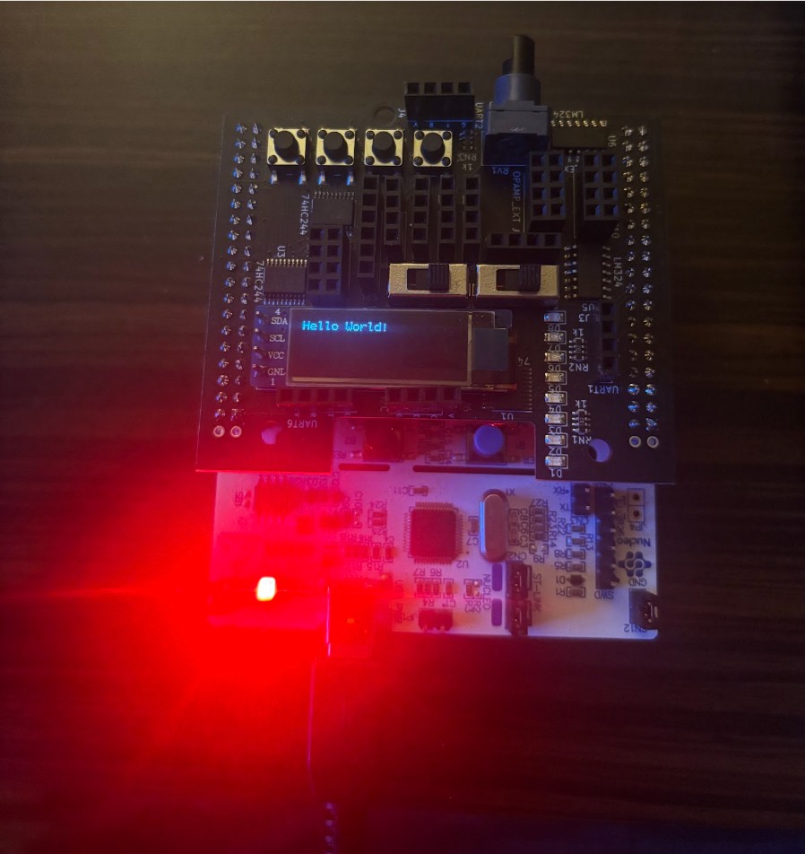 STM32 Nucleo with black expansion shield and OLED showing Hello World